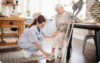 Caregiver assisting elderly woman with crutches at home