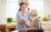 Caregiver assisting elderly woman in a bright home setting