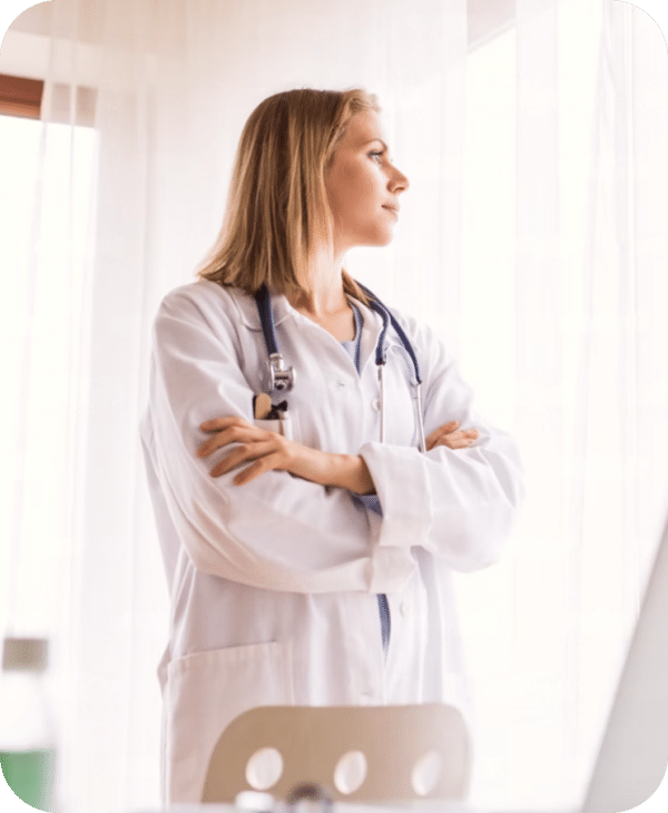 Doctor in white coat gazing thoughtfully out a window