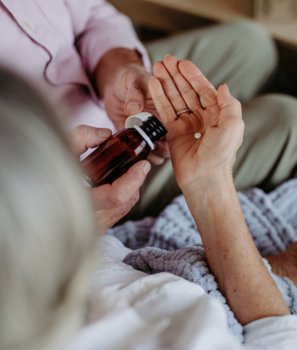 Elderly person receiving medication at home from caregiver
